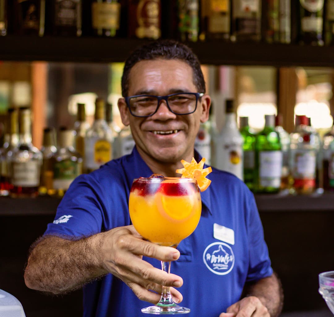 Bartender do Restaurante do Vale servindo drink autoral de maracujá no bar em Fernando de Noronha